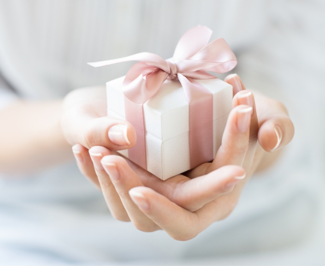 Person opening a gift card box wrapped with a bow